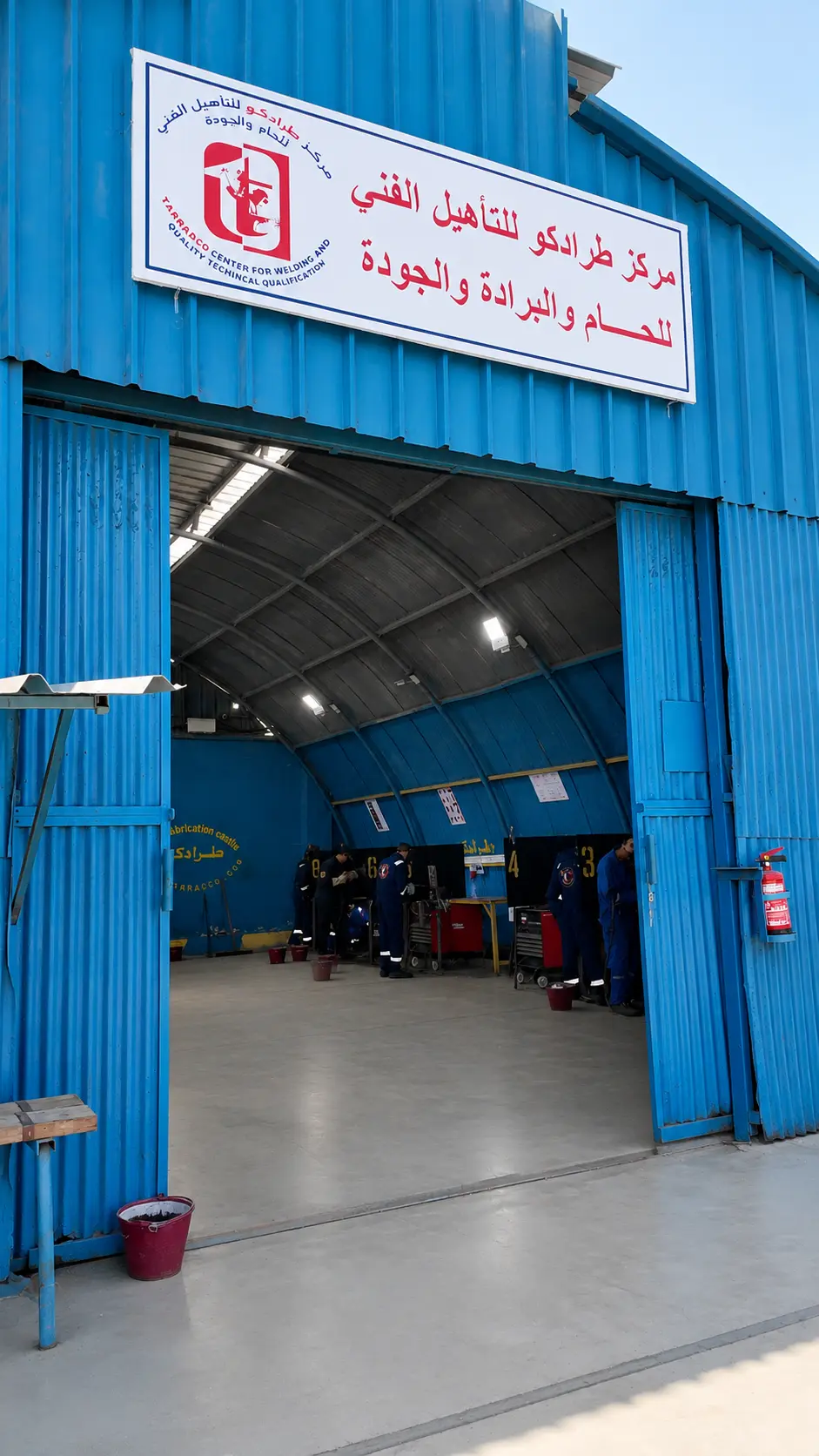 Bilingual signboard reading Tarradco Center for Welding and Quality Technical Qualification above the workshop entrance