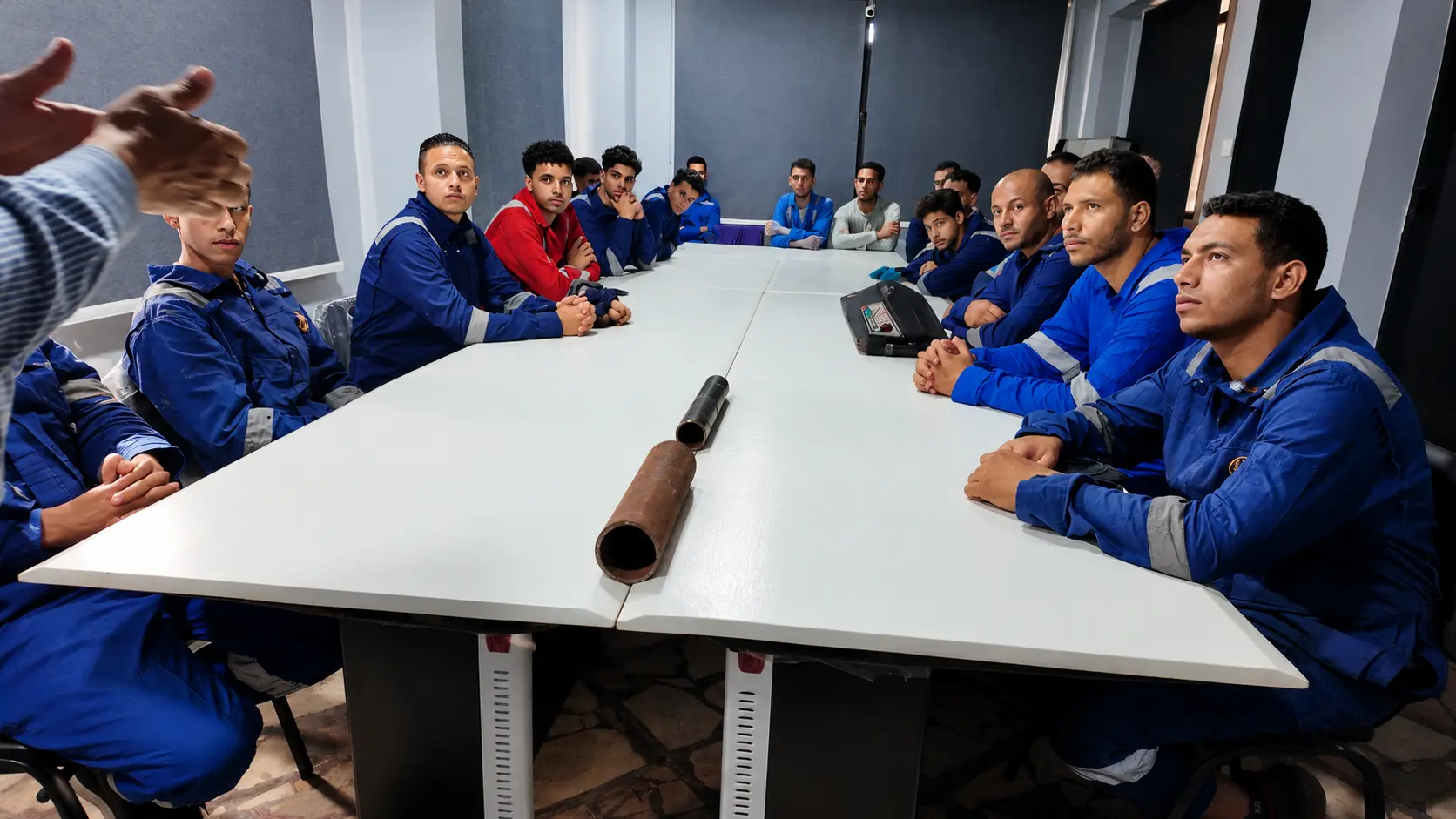 Theory session with a cut pipe coupon on the table used to explain welding procedures to trainees